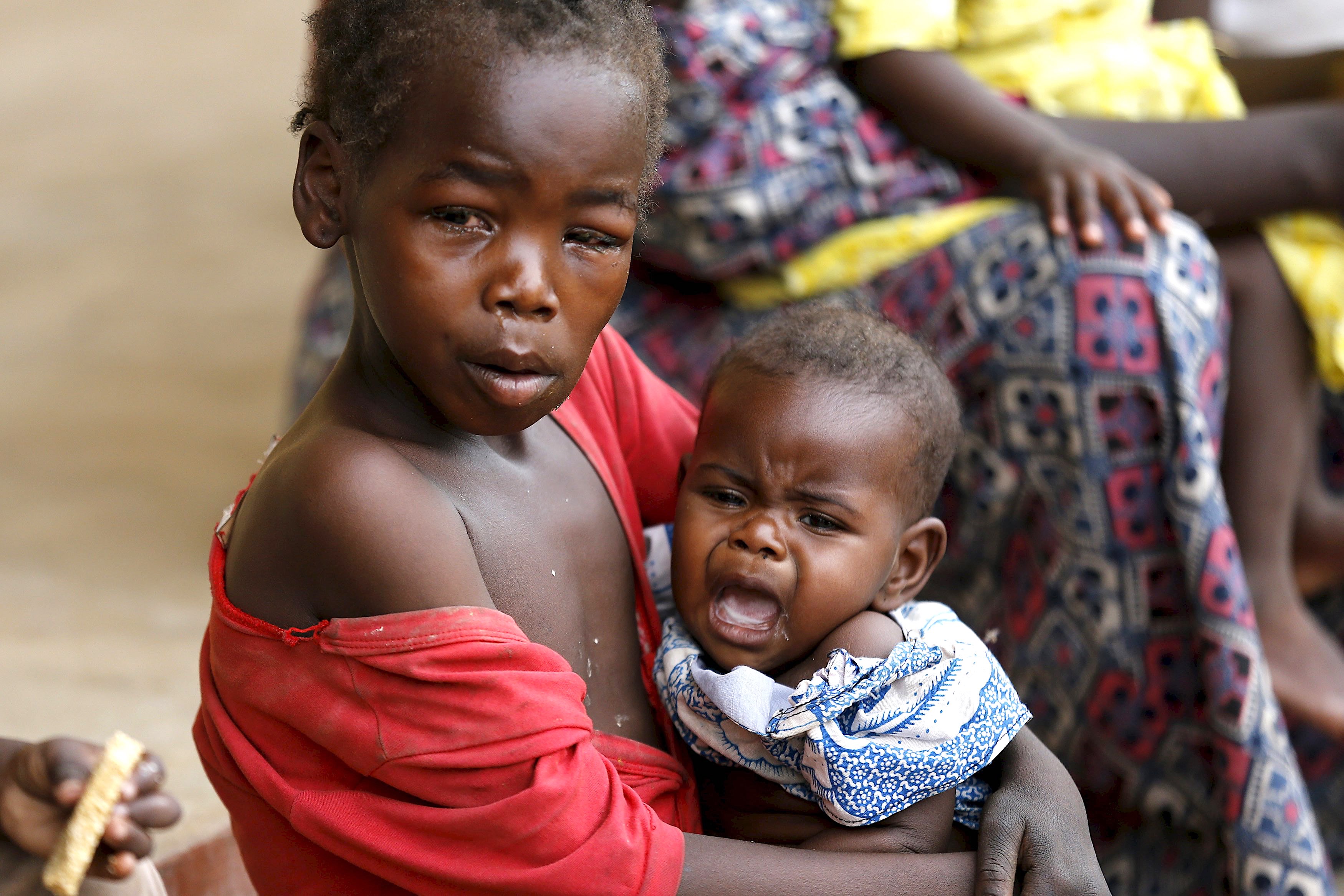A child rescued from Boko Haram in Sambisa forest carries a baby in front of a clinic at the Malkohi camp for Internally Displaced People in Yola, Adamawa State, Nigeria May 3, 2015. Hundreds of traumatised Nigerian women and children rescued from Boko Haram Islamists have been released into the care of authorities at a refugee camp in the eastern town of Yola, an army spokesman said. REUTERS/Afolabi Sotunde